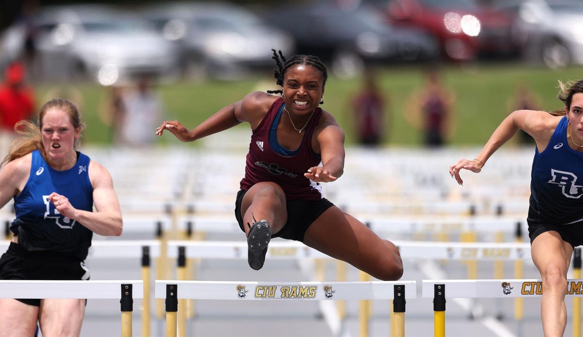Makiyah Allen clears a hurdle during a track meet, pushing ahead of competitors as she focuses on her own performance and pace.